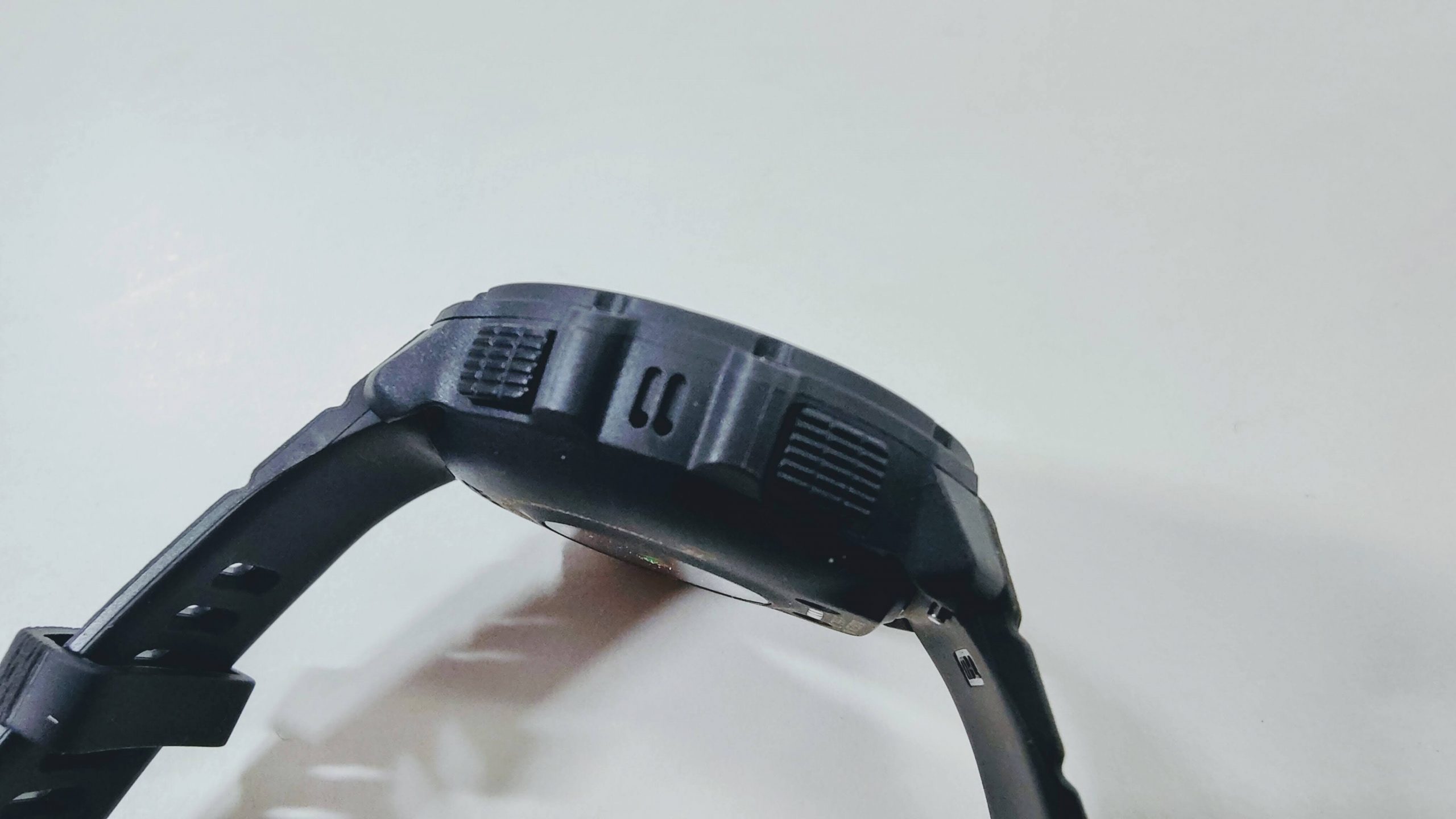 Side view of a black rugged sports watch with buttons and vented case on the side of the strap