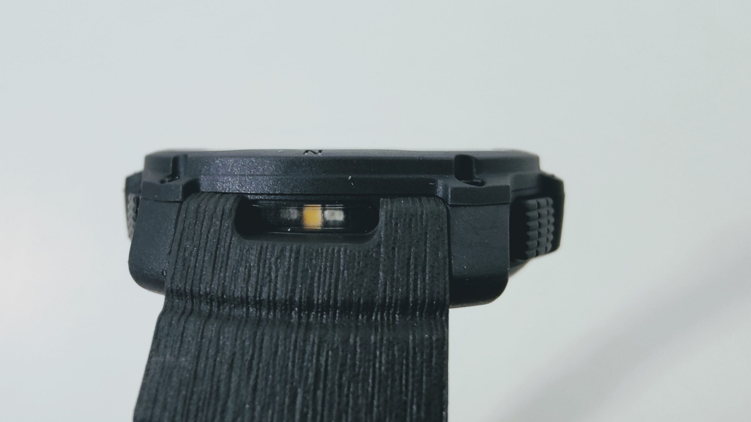 Close-up of a black strap-connected device with a small orange element visible in a recessed window