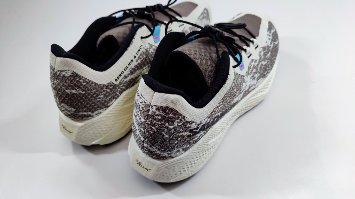 Pair of athletic running shoes with a gray and black speckled pattern and white soles, viewed from the back/side edge.