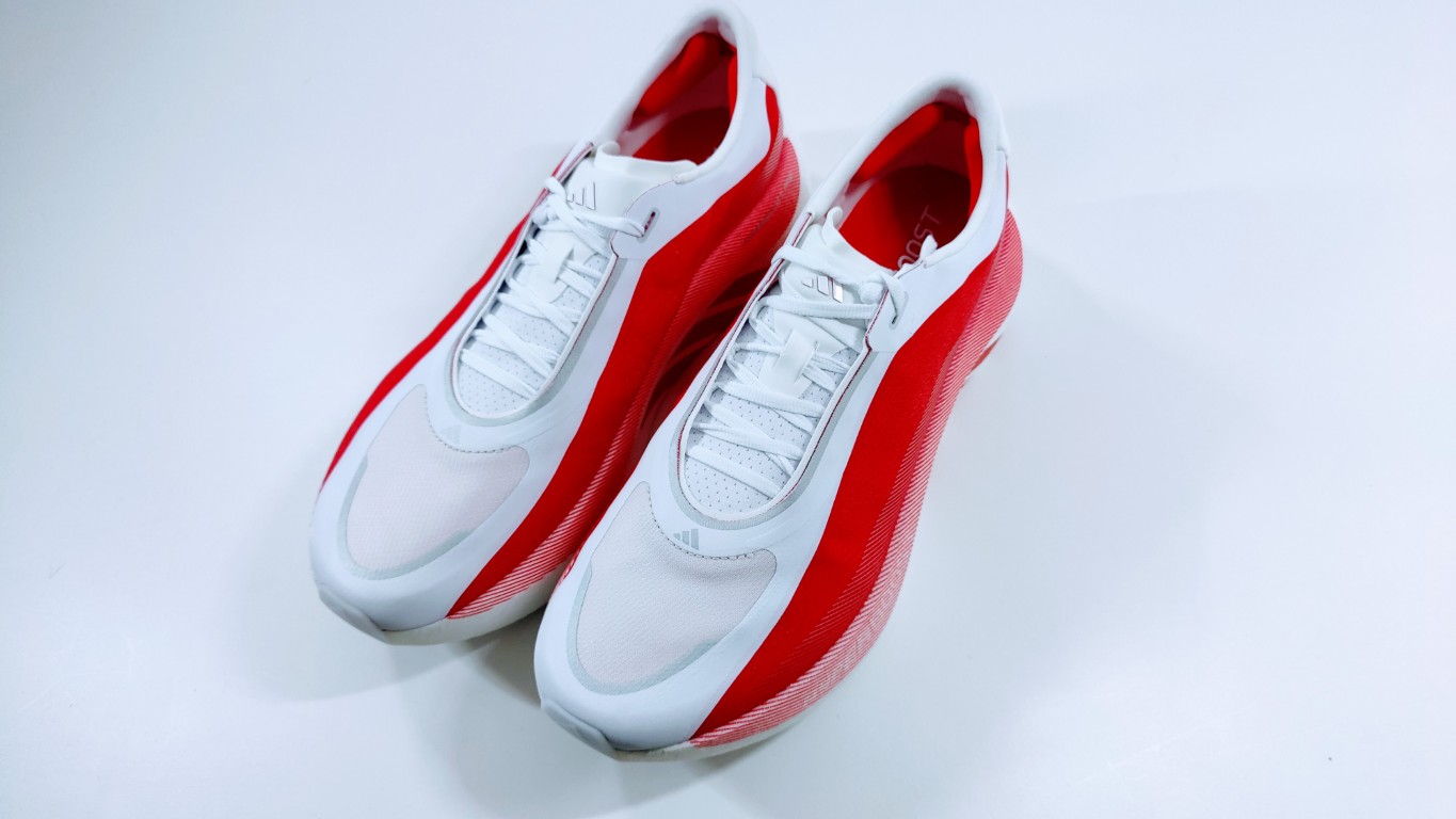 Pair of white and red athletic sneakers seen from above on a light surface