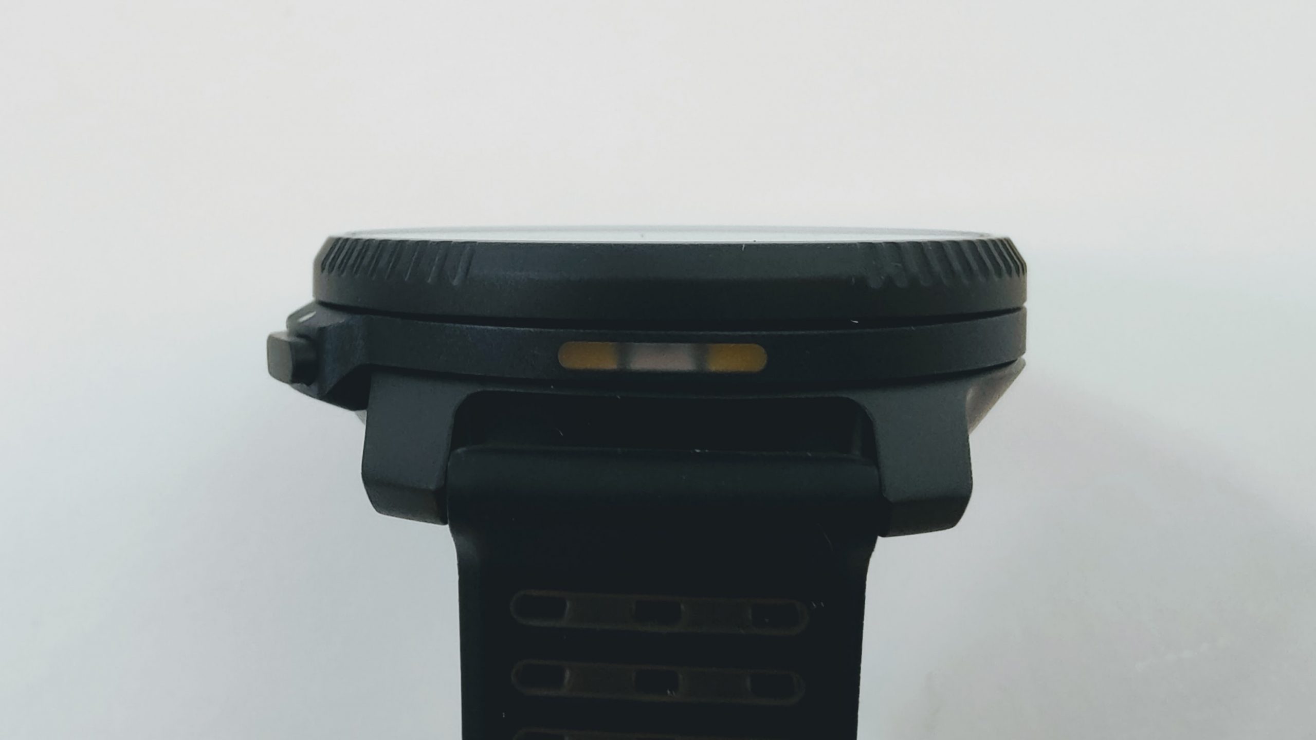 Close-up of a black wristwatch with a ridged rotating bezel on a white background