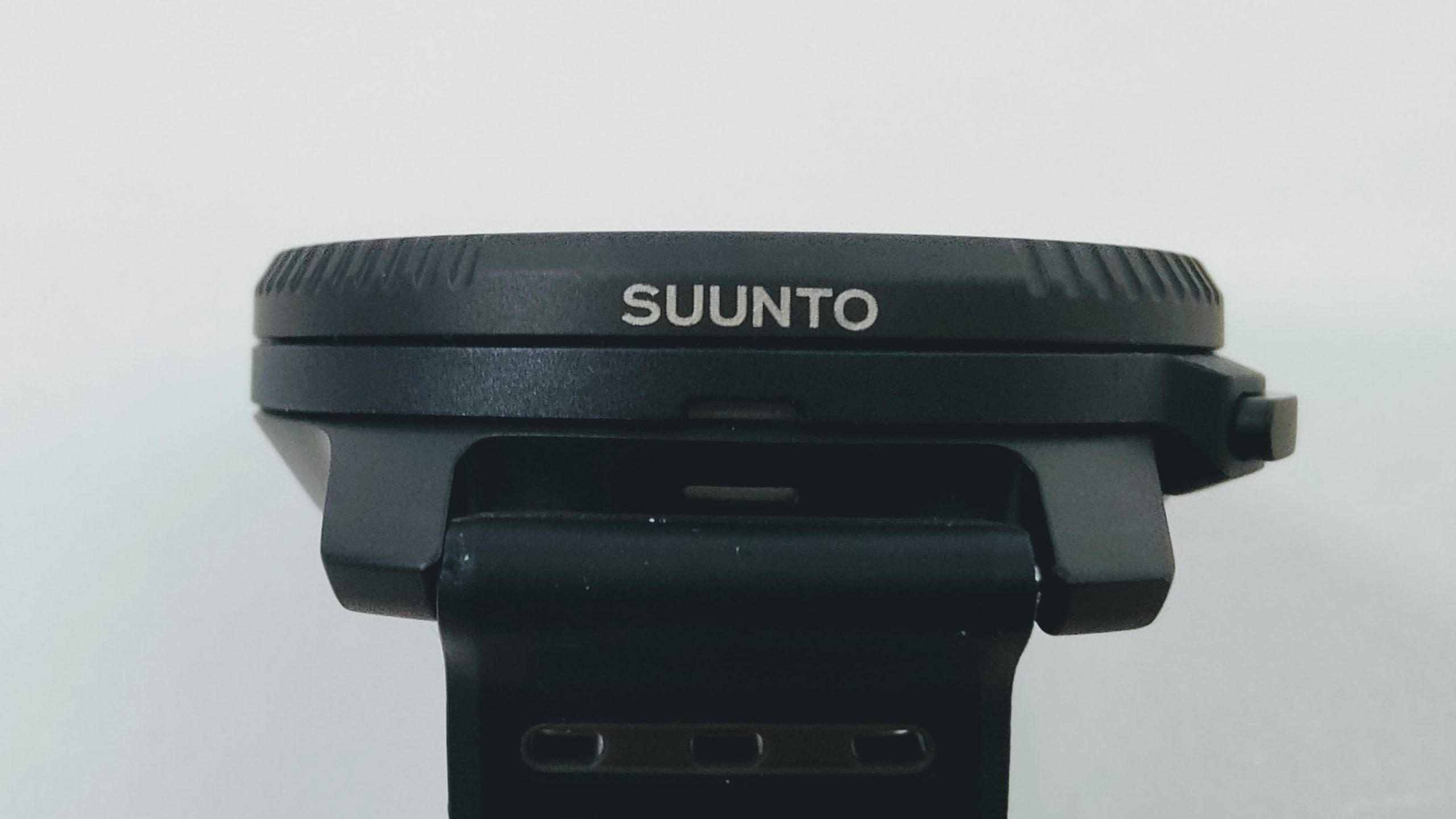 Close-up of a Suunto watch bezel with a textured edge, viewed from the side against a white background.
