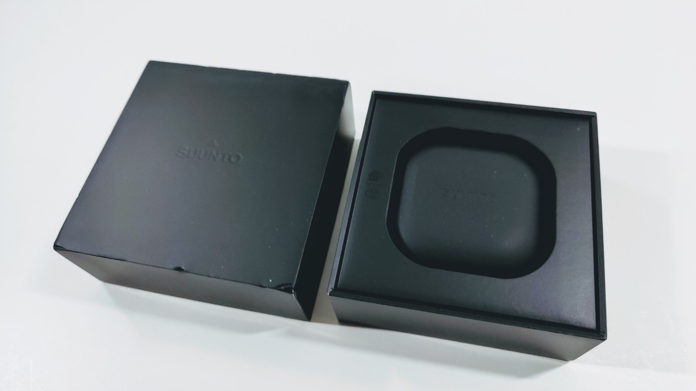 Two black boxes on a white surface; the left box is closed, the right box is open showing a rounded-square molded insert inside.