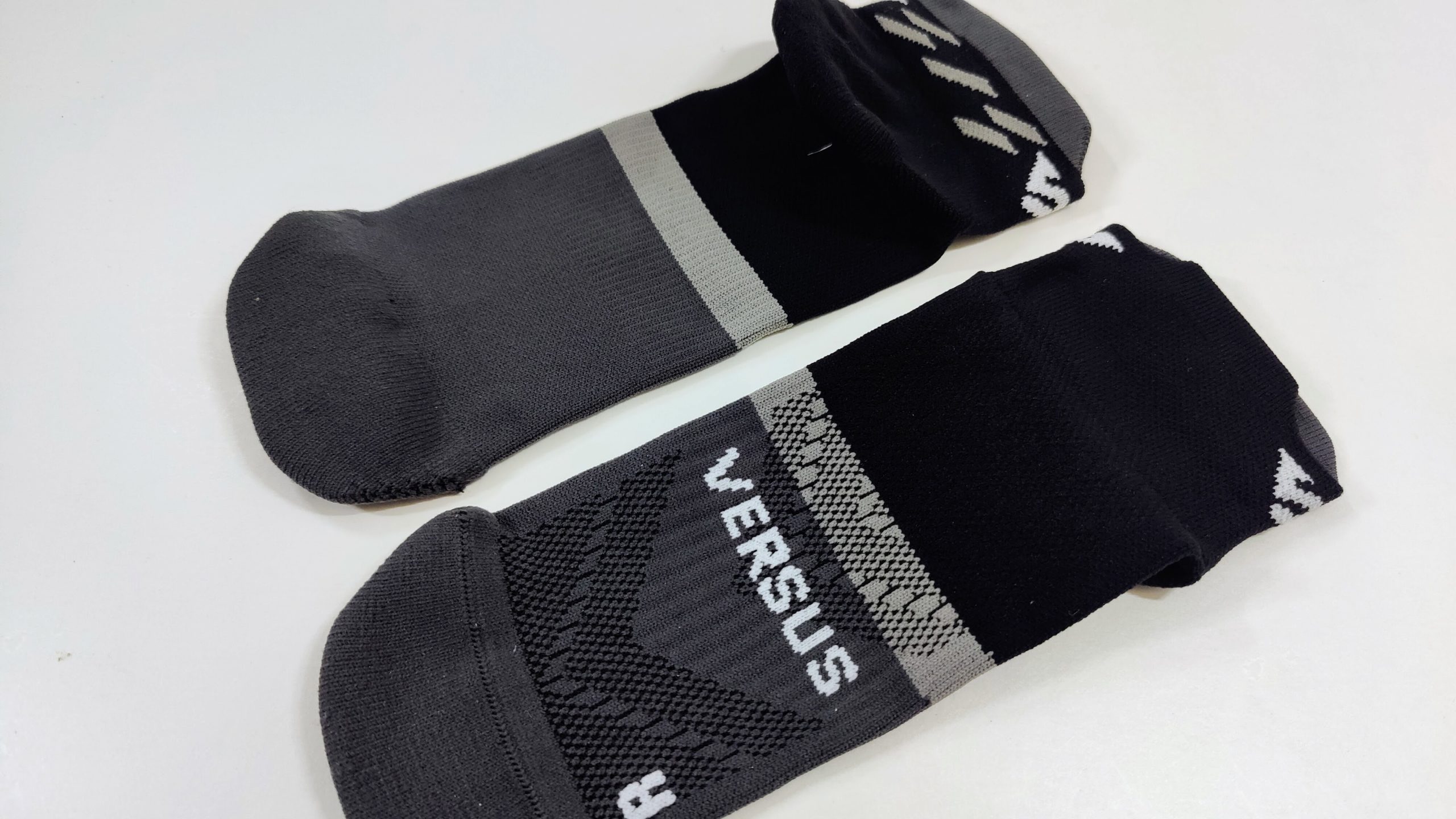 Pair of dark gray and black athletic socks with a light gray band, laid on a white surface.