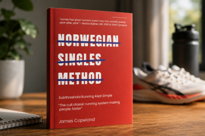 Red hardcover book on a wooden desk with bold white title 'NORWEGIAN SINGLES METHOD' crossed by blue lines; blurred plant, notebook, sneakers, and shaker bottle in the background.