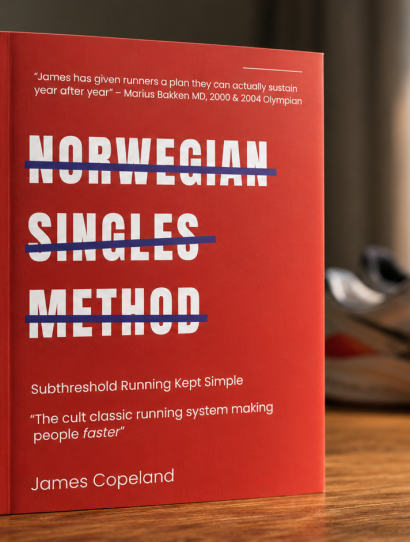 Red hardcover book on a wooden desk with bold white title 'NORWEGIAN SINGLES METHOD' crossed by blue lines; blurred plant, notebook, sneakers, and shaker bottle in the background.