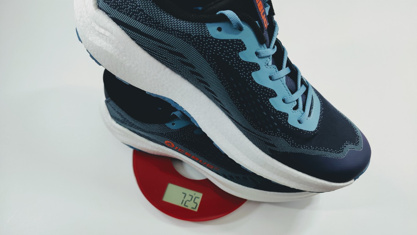 Running shoe in navy and light blue rests on a red digital scale displaying 725 g (weight). They show a close-up of the shoe on the scale.