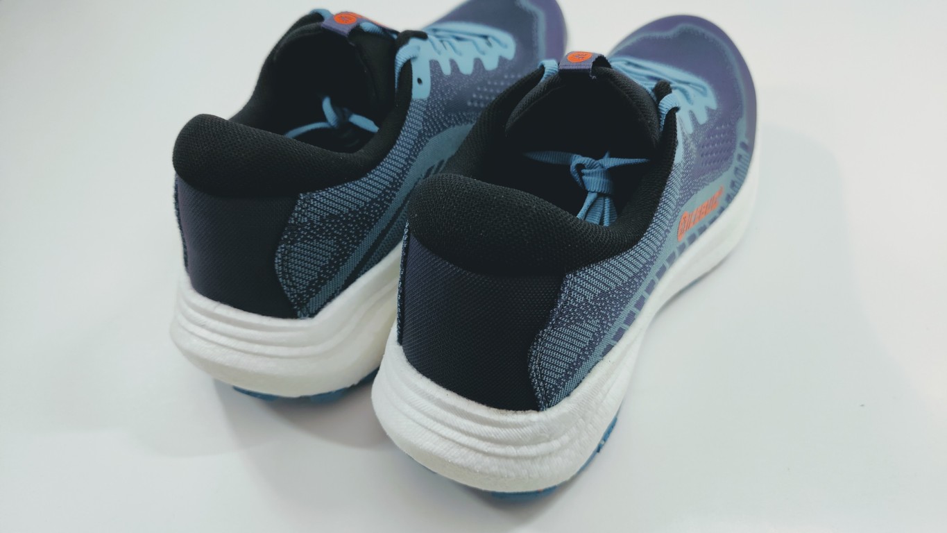Pair of blue and black running shoes viewed from the back on a white surface, showing white midsoles and padded heels.