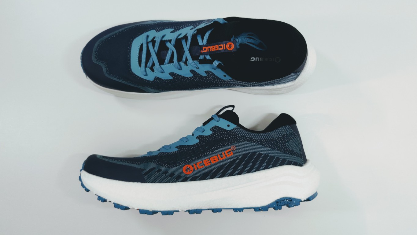 Two blue Icebug running shoes on a white surface, shown from top and side with light blue laces and orange logo accents.