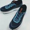 Pair of blue athletic running shoes with light blue laces on a white surface, arranged diagonally.