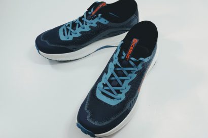 Pair of blue athletic running shoes with light blue laces on a white surface, arranged diagonally.