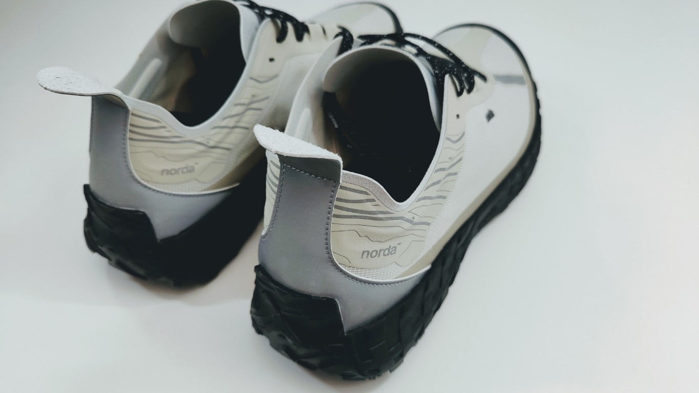 Light gray Nordic trail running shoes with black chunky soles photographed from the back, Norda branding visible on the heel area.