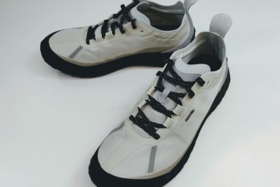Light beige running shoes with black laces and gray accents on a white surface.