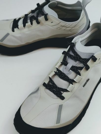 Light beige running shoes with black laces and gray accents on a white surface.