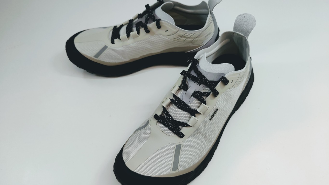 Light beige running shoes with black laces and gray accents on a white surface.