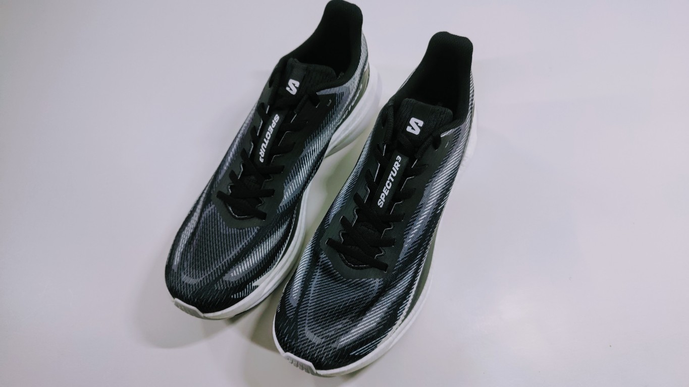 Pair of black running shoes with white midsoles and gray patterned uppers on a light surface
