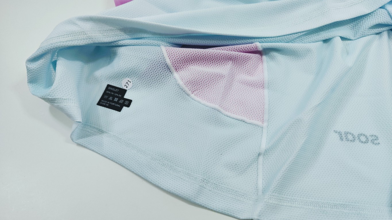 Light blue mesh athletic shirt with a small size tag and a pink inner mesh panel visible at the seam.