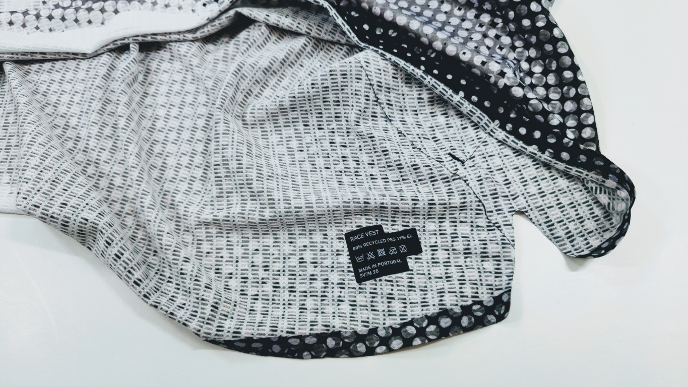 Close-up of a black-and-white fabric with a dotted outer edge and a small tag reading 'RACE VEST' and 'Made in Portugal' on the inside.