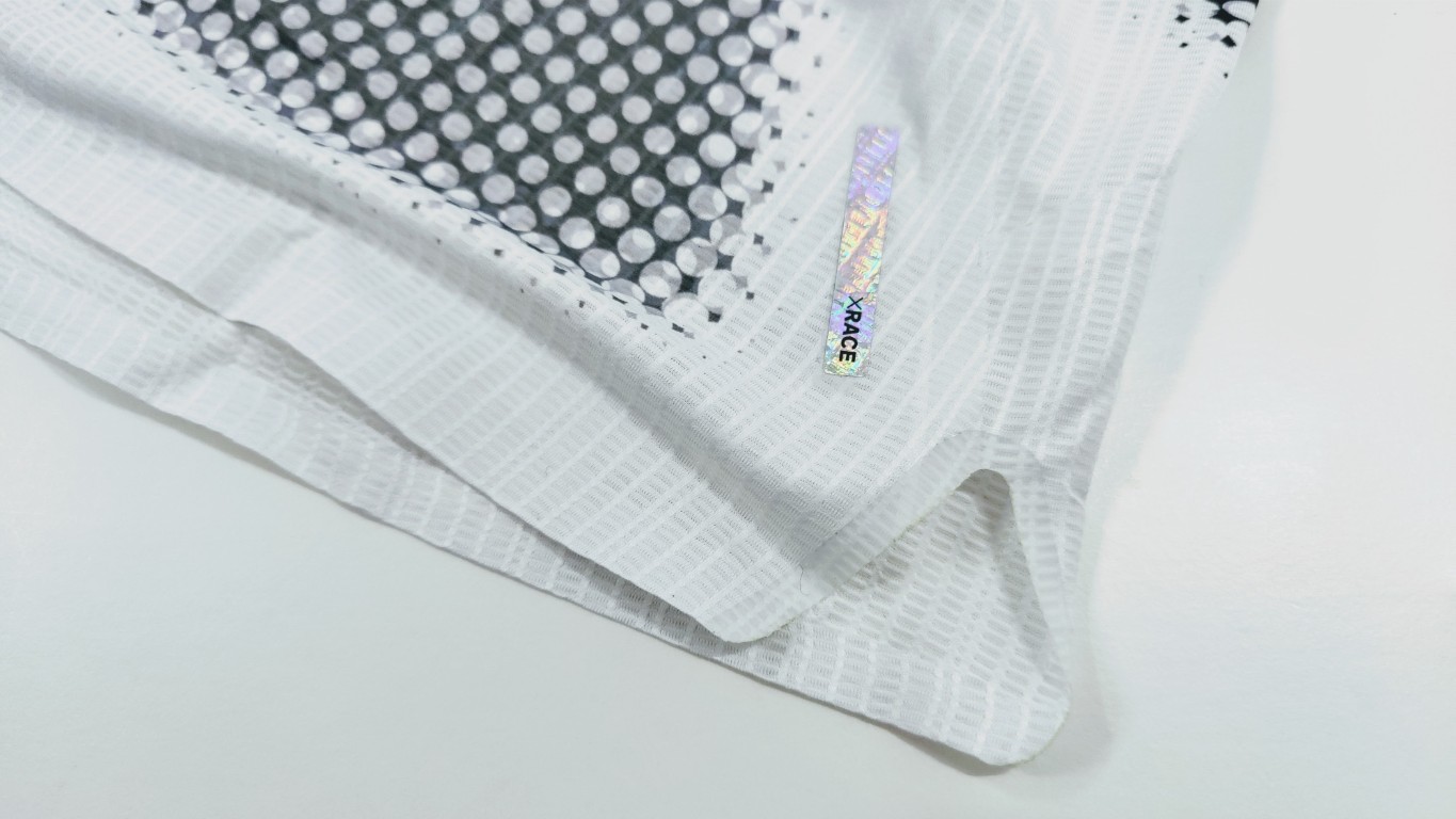 Close-up of white mesh athletic fabric with a holographic XRACE tag.