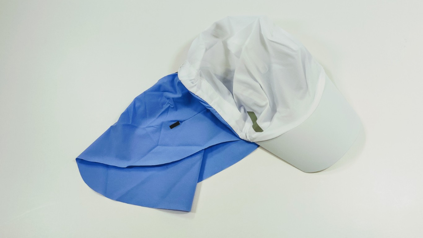 White baseball cap with a light blue detachable neck scarf hanging behind it.