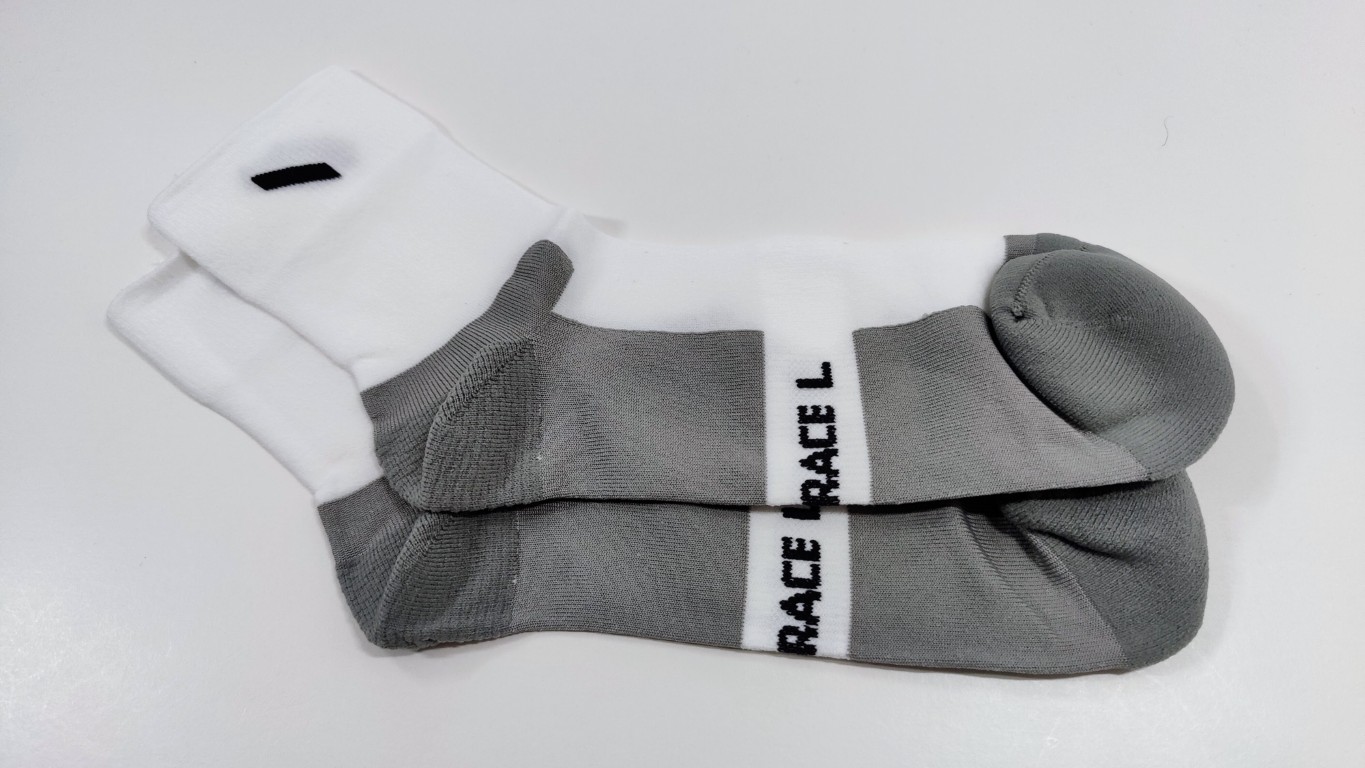 Pair of white ankle running socks with grey foot sections and a 'RACE L' band, lying on a white surface.