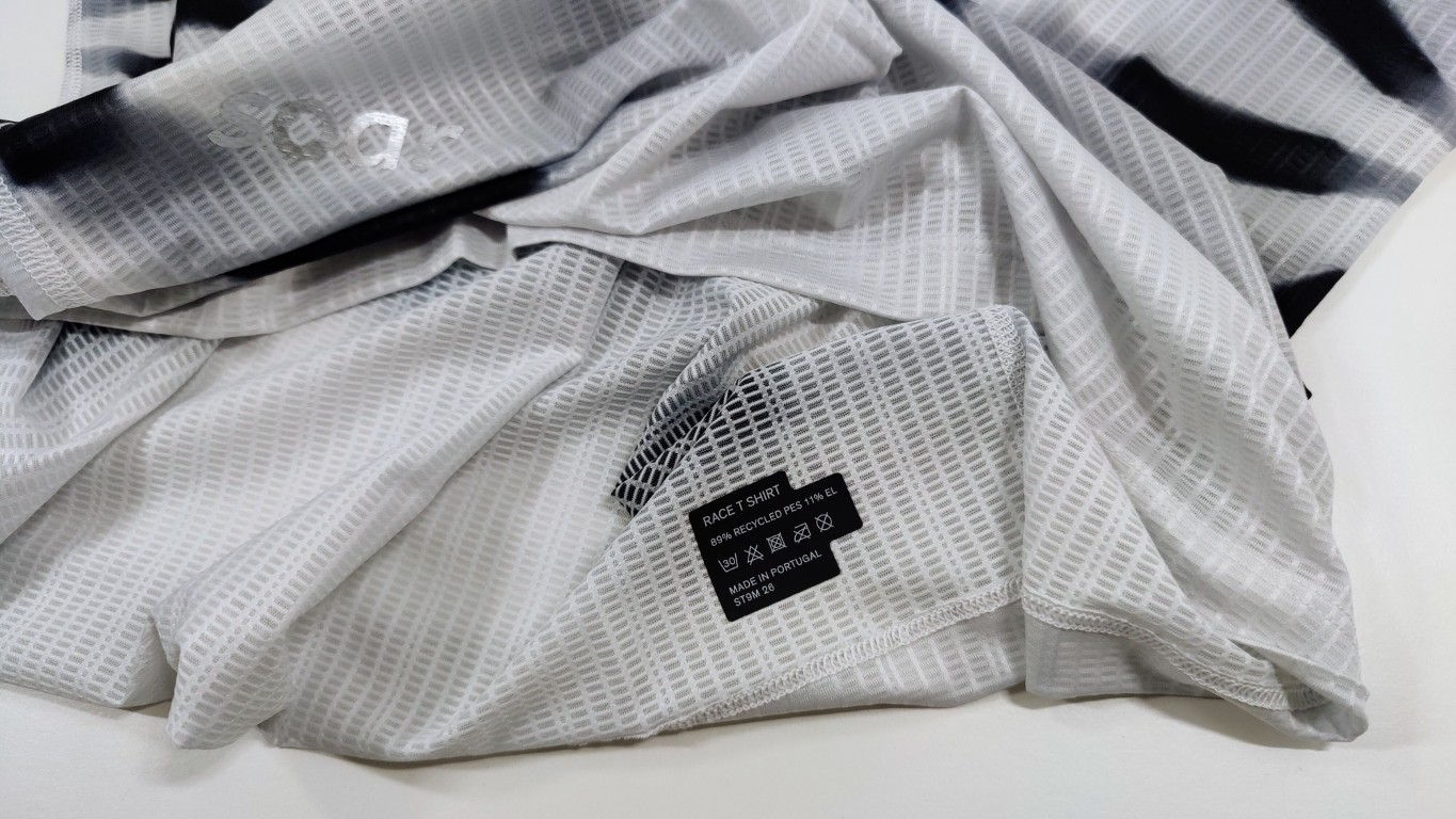 Close-up of white ribbed mesh fabric with a black care label near the hem.