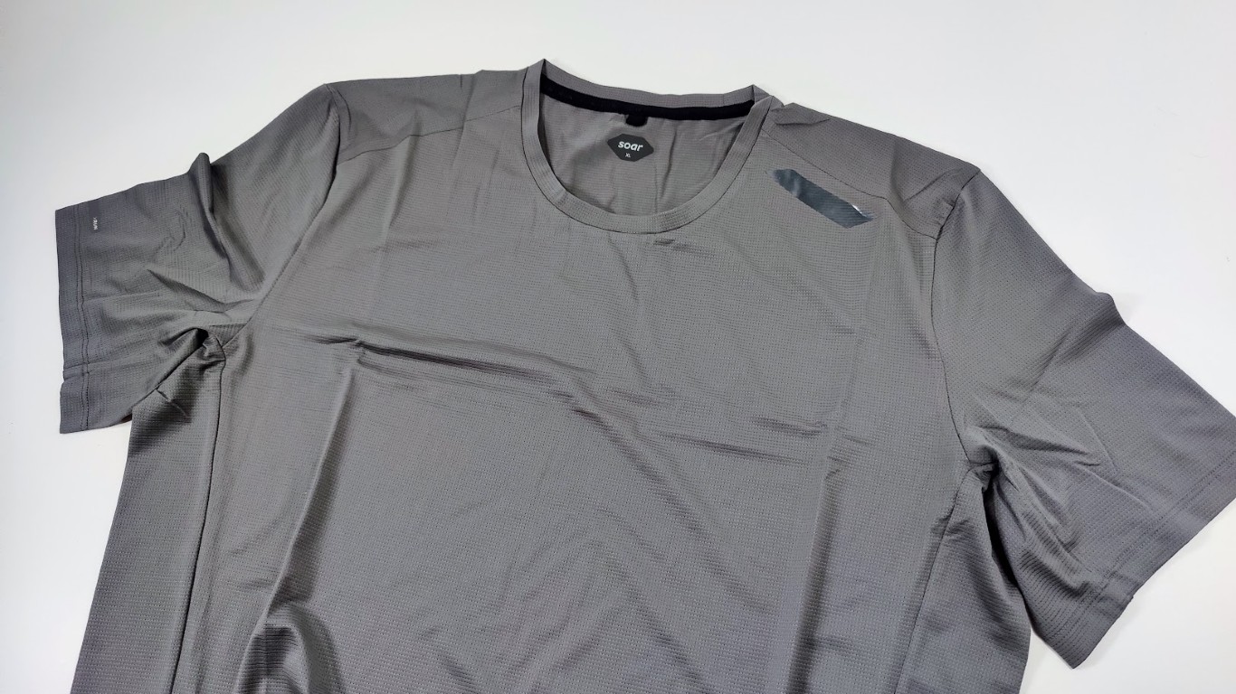 Grey short-sleeve running T-shirt laid flat on a white surface, with a small reflective logo on the chest.