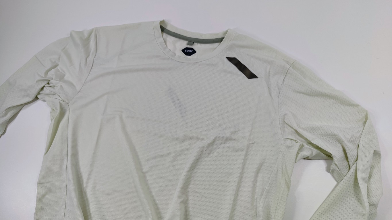 Cream long-sleeve running shirt laid flat on a white surface, showing the round neckline and fine mesh fabric.