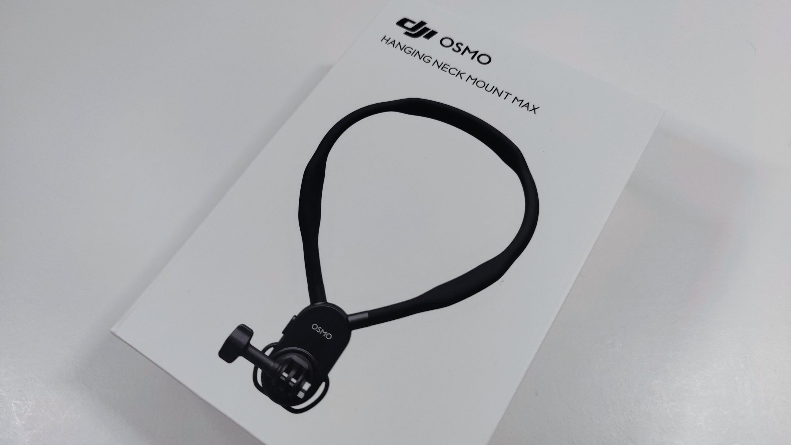 Retail box of the DJI Osmo Hanging Neck Mount Max on a white surface.