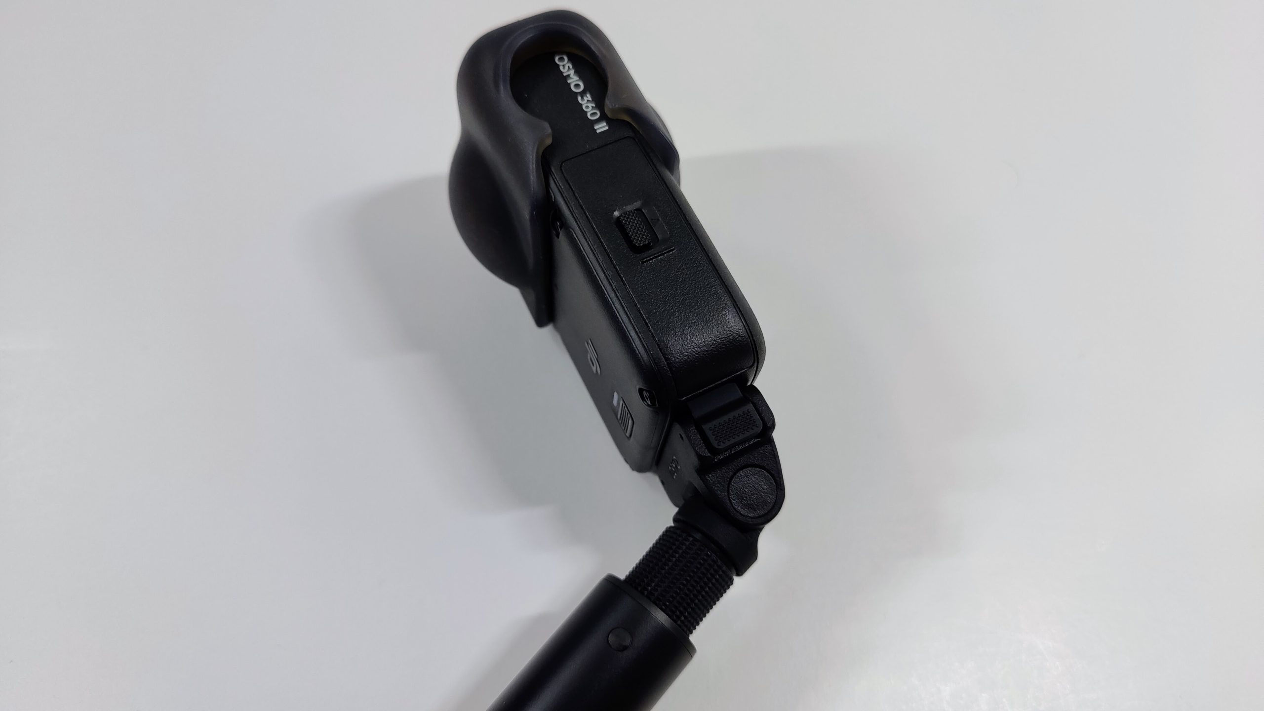 Compact 360 camera mounted on a folding quick-release adapter on a black selfie stick.