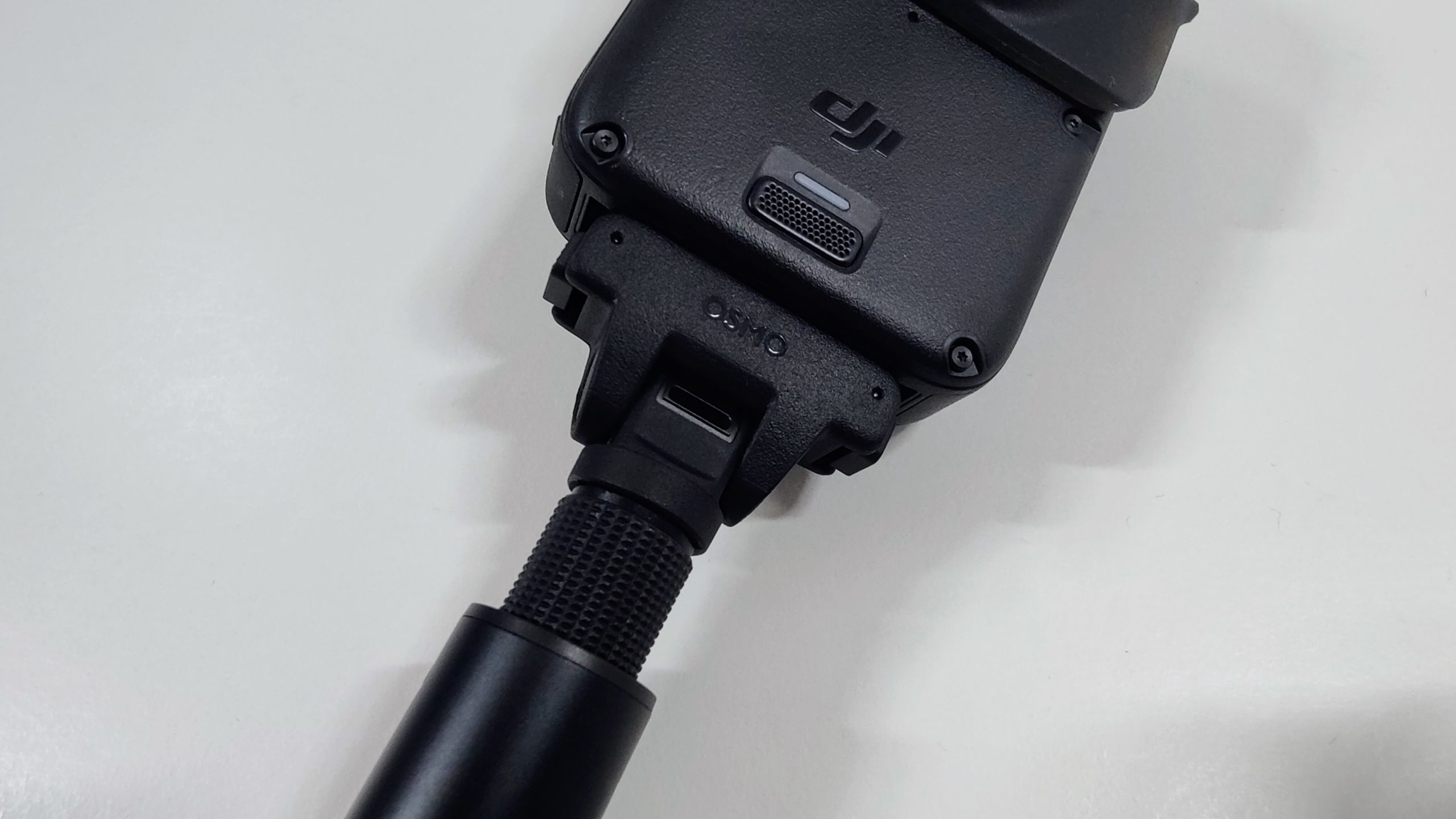 Underside of a 360 camera attached to a telescopic selfie stick via a magnetic quick-release mount.