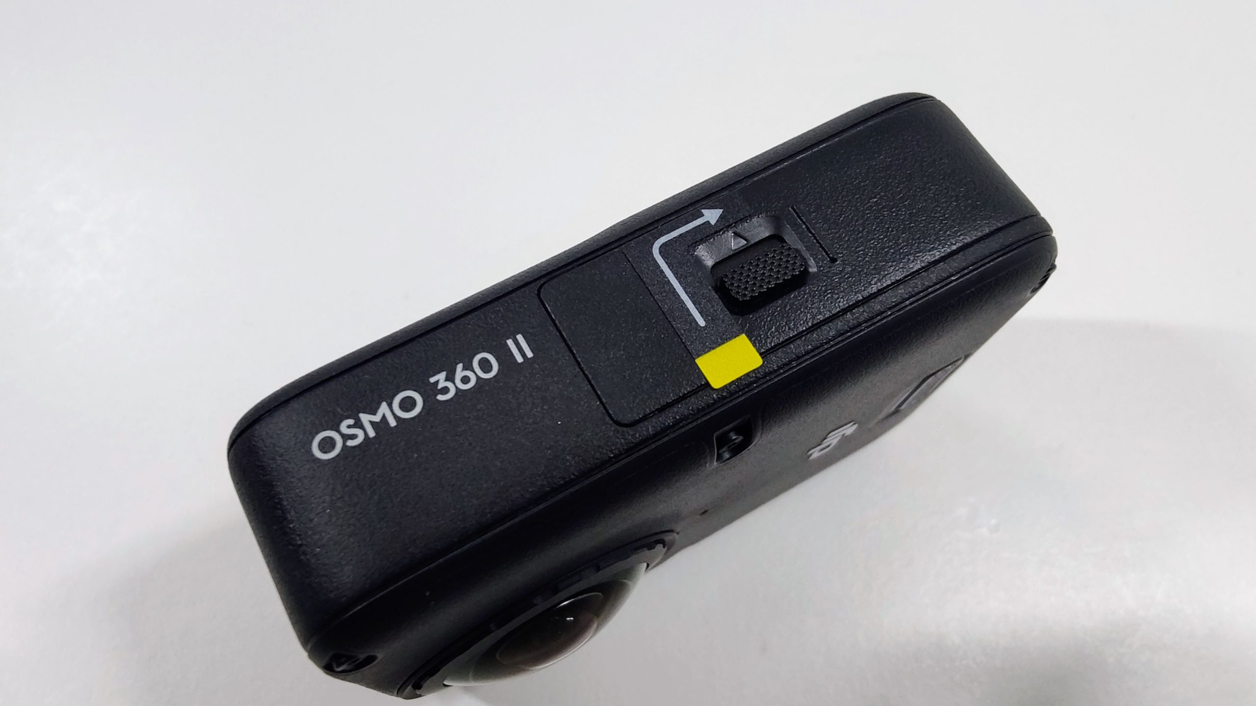Side of the camera labeled Osmo 360 II with a quick-release slider and a yellow tab.