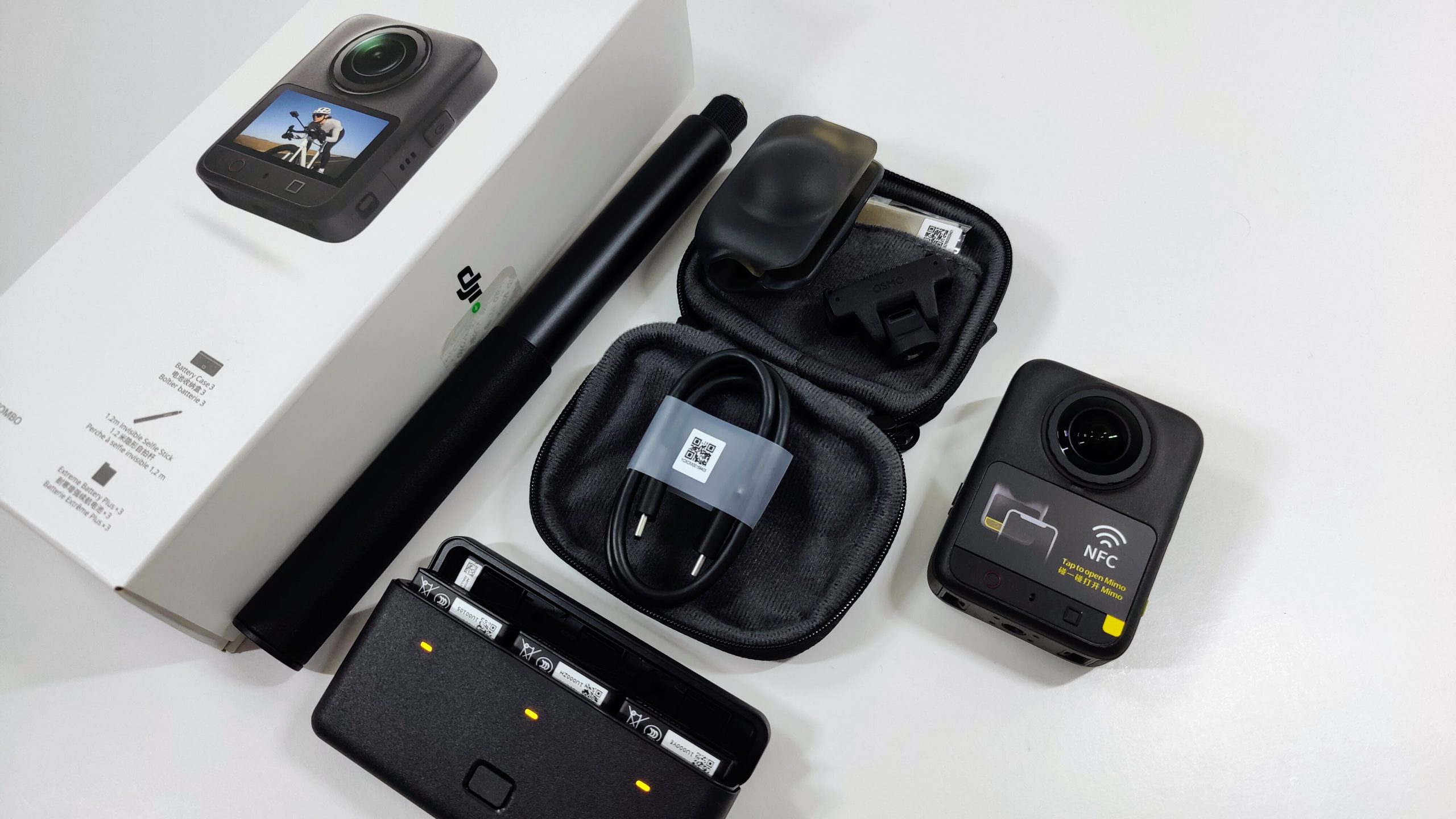 Adventure Combo contents laid out: camera, selfie stick, battery charging case, carry pouch and cable.