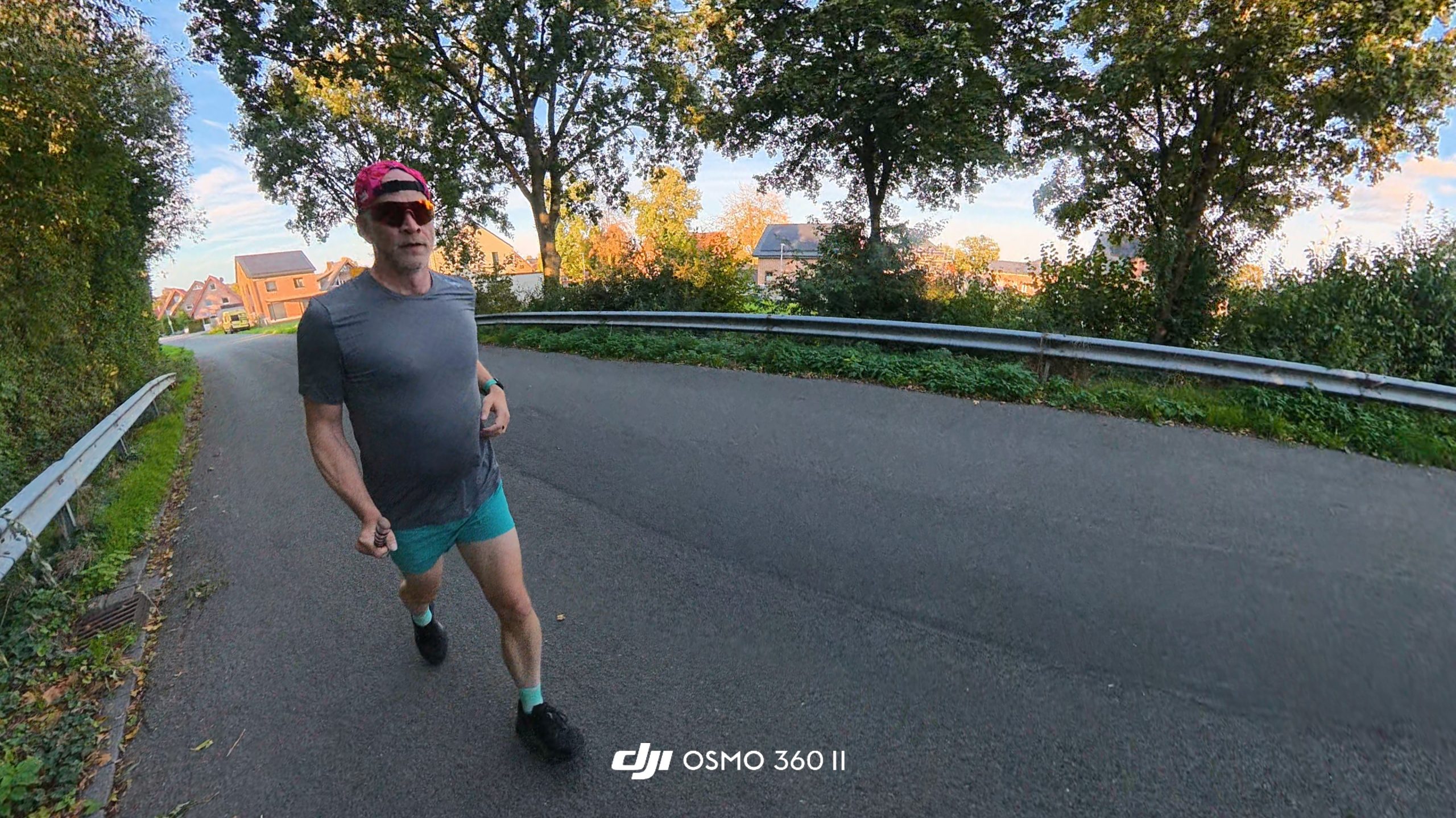 Runner seen from a high angle on an asphalt road lined with trees and a guardrail.